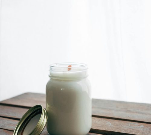 A simple jar candle with wooden wick on rustic table.